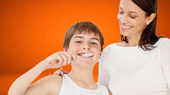 madre e figlio su sfondo arancione il figlio si lava i denti